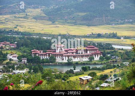 Vue de Punakha Dzong entouré de deux rivières avec une mosaïque de rizières en terrasses et de montagnes boisées au loin dans le Royaume du Bhoutan Banque D'Images