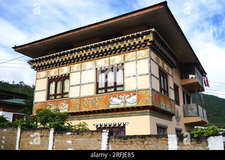 Architecture bhoutanaise typique avec toit en surplomb carré, charpente en bois, chevrons saillants peints, fenêtres triplées et peintures murales décoratives Banque D'Images