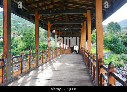 En regardant à travers le pont en bois couvert historique menant à travers la rivière Mo Chhu à l'ancien Punakha Dzong dans le Royaume du Bhoutan Banque D'Images