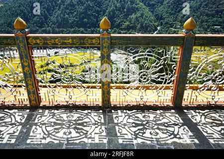 Une grille métallique décorative projette une ombre de la roue bouddhiste à huit rayons sur le sol en pierre au sommet de Khamsum Yulley Namgyal Chorten dans la campagne du Bhoutan. Banque D'Images