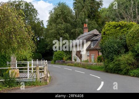 Scène rurale calme avec une route sinueuse et maison de chaume entourée d'arbres dans le village de Cheriton dans le Hampshire, en Angleterre. Août 2023. Banque D'Images