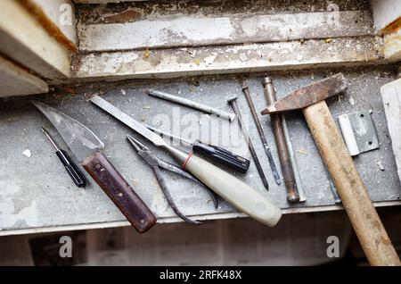 Réparation de l'ancienne fenêtre endommagée ou démontage avant l'installation d'une nouvelle fermeture. Réparation d'un cadre de fenêtre, à l'aide d'instruments pour la rénovation de vieilles fenêtres Banque D'Images