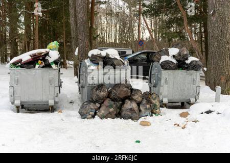 des conteneurs à ordures débordant sur le site autour desquels les ordures et les sacs de déchets sont dispersés. Mauvaise performance des services publics. Banque D'Images