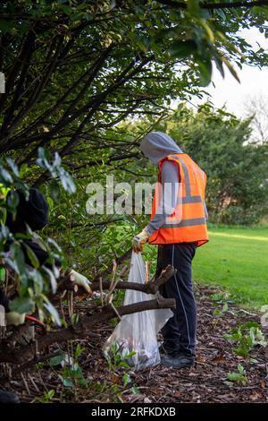 Les sacs en plastique remplis de déchets sont retirés des terrains d’un centre sportif par l’équipe Community Payback. Banque D'Images