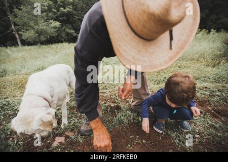 Agriculteur avec chien et Grandson planter des graines Banque D'Images