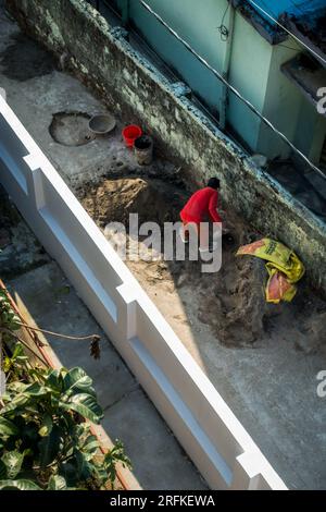 14 octobre 2022 Uttarakhand, Inde. Vue plongeante d'un homme travaillant sur un chantier de construction, remplissant du sable à la main dans la ville de Dehradun. Dur labeur en cours. Banque D'Images