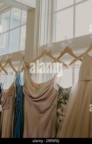 Robes de demoiselle d'honneur accrochées à des cintres devant la fenêtre Banque D'Images