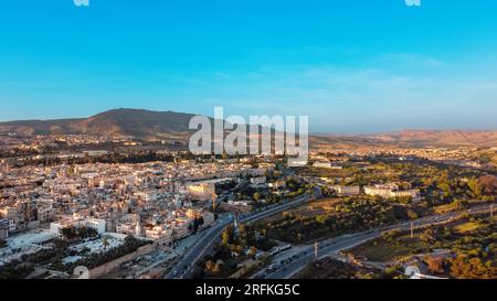 Vue aérienne drone de Fès au coucher du soleil, Maroc. Plusieurs bâtiments résidentiels faits dans le style national, verdure, collines rocheuses autour Banque D'Images