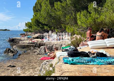 Porec, Kroatien. 30 juillet 2023. Plava Laguna, côte Adriatique près de Porec/Croatie, plage. Les vacanciers sont sur la plage de pierre, plage rocheuse au soleil et se détendre, se détendre. ? Crédit : dpa/Alamy Live News Banque D'Images