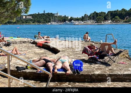 Porec, Kroatien. 30 juillet 2023. Plava Laguna, côte Adriatique près de Porec/Croatie, plage. Les vacanciers sont sur la plage de pierre, plage rocheuse au soleil et se détendre, se détendre. ? Crédit : dpa/Alamy Live News Banque D'Images