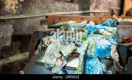 Déchets plastiques sur un tapis roulant dans une usine de recyclage des déchets Banque D'Images