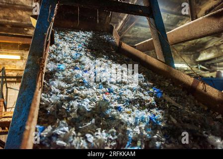 Déchets plastiques sur un tapis roulant dans une usine de recyclage des déchets Banque D'Images