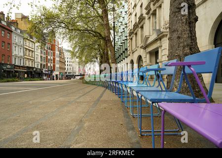 Londres, Angleterre, Royaume-Uni - 8 mai 2023. Des chaises arc-en-ciel colorées bordent une place londonienne sur Strand Street, Aldwych, près de l'église St Mary le Strand. Banque D'Images