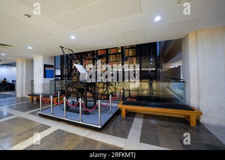 Londres, Angleterre, Royaume-Uni - 31 juillet 2022. Intérieur de la British Library avec une ancienne machine à imprimer antique, matériel d'impression exposé, étagères à livres Banque D'Images