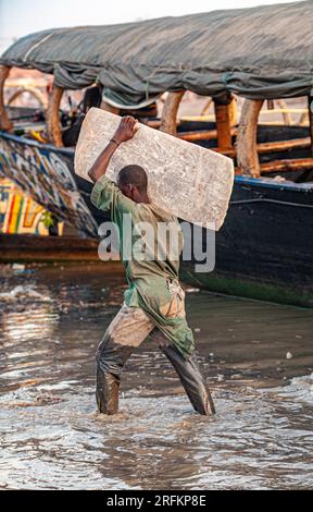 Homme portant une dalle de sel sur l'épaule. Le sel vient avec des chameaux des mines de sel de Taoudeni. Mopti , Mali , Afrique de l'Ouest Banque D'Images