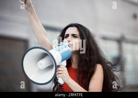 Mégaphone, femme et criant pour le changement social, la justice pour l'égalité et l'humanité avec activiste dans la rue, debout et grève. Jeune femme Banque D'Images