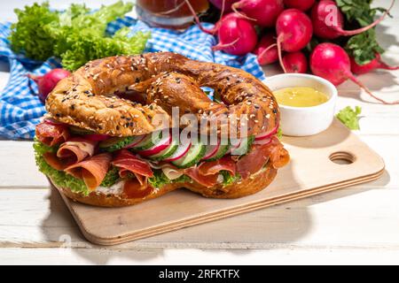 Sandwich au bagel Oktoberfest bretzel. Petit déjeuner Oktoberfest, recette de hamburger pour les fêtes de fête de la bière. Grand bretzel avec jambon, fromage, légumes frais, W Banque D'Images