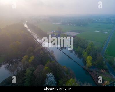 Plongez dans la beauté enchanteresse d'une matinée mystique tandis que la caméra panoramique sur une vue aérienne captivante d'une rivière, d'un champ de ferme et d'un paysage forestier. Sous l'étreinte douce du brouillard matinal, la sereine rivière serpente à travers les champs verdoyants de la ferme et la forêt majestueuse. Alors que le soleil se lève, ses rayons dorés traversent la brume, projetant une lueur chaude et éthérée sur le paysage. Ce panoramique capture l'essence de la tranquillité et l'attrait de l'éveil de la nature. Découvrez la beauté sereine et l'ambiance captivante de cette scène magique du matin, où le jeu de brouillard Banque D'Images