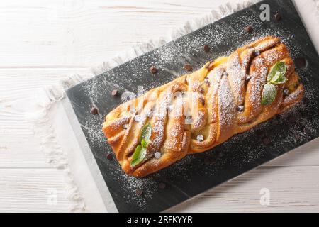 Savoureux petit pain tressé avec chocolat et crème anglaise gros plan sur une planche d'ardoise sur la table. Vue de dessus horizontale Banque D'Images