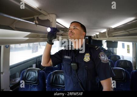 Laredo, États-Unis. 31 juillet 2023. UN AMÉRICAIN Un agent des douanes et de la protection des frontières inspecte un autobus pour détecter la contrebande au poste frontalier du Mexique, le 31 juillet 2023 à Laredo, au Texas. Crédit : Glenn Fawcett/CBP photos/Alamy Live News Banque D'Images