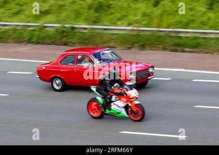 Honda CBR moto dépassant une Ford des années 1970 70 seventies Red Ford Escort Lotus essence 1558 cc roulant à grande vitesse sur l'autoroute M6 dans le Grand Manchester, Royaume-Uni Banque D'Images
