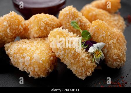 Nuggets de fromage frits avec sauce aux baies, sur fond sombre Banque D'Images