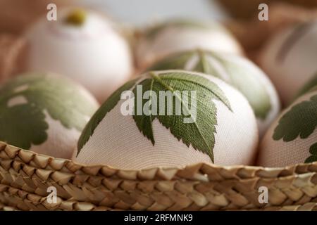 Oeufs de Pâques avec des feuilles fraîches attachées à eux - préparation pour la teinture avec des pelures d'oignon Banque D'Images