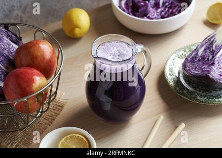 Jus de chou violet dans une cruche en verre avec des pommes et du citron Banque D'Images