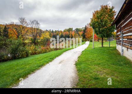 Sentier de gravier vide sur les berges d'une rivière par une journée nuageuse d'automne. De superbes couleurs d'automne sont le long de la rivière. Banque D'Images