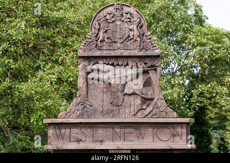 Le panneau de village sculpté en bois pour le village de West Newton sur le domaine de Sandringham dans le Norfolk. Banque D'Images