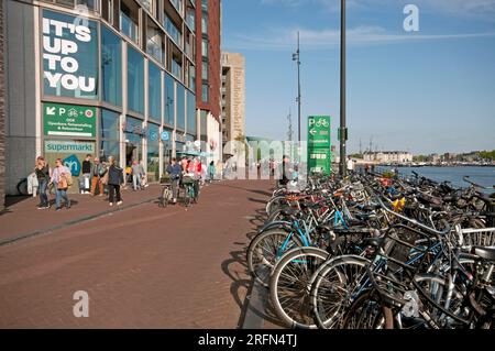 Les gens marchent et font du vélo à Oosterdokskade (en arrière-plan le Musée des Sciences Nemo), Amsterdam, pays-Bas Banque D'Images