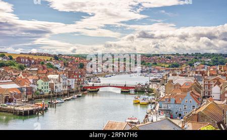 Port de Whitby et ville donnant vers l'intérieur. Les bâtiments de la ville se regroupent autour du port et un pont s'étend sur l'eau. Un ciel nuageux est au-dessus. Banque D'Images