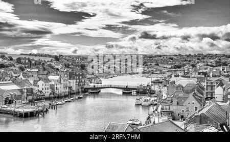 Port de Whitby et ville donnant vers l'intérieur. Les bâtiments de la ville se regroupent autour du port et un pont s'étend sur l'eau. Un ciel nuageux est au-dessus. Banque D'Images