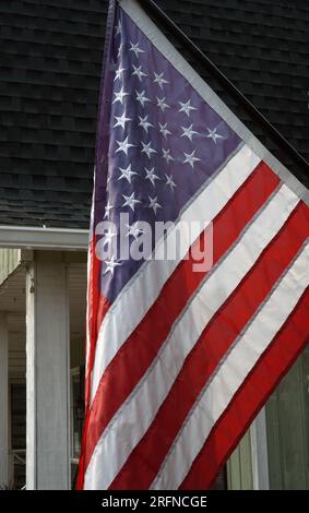 Un drapeau américain étoiles et rayures est accroché devant une maison Banque D'Images