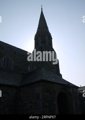 Lostwithiel (Lostwydhyel), Cornouailles (Kernow), Royaume-Uni - la tour de l'église St Bartholomew en silhouette, avec horloge et girouette de coq. Banque D'Images