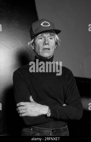 Andy Warhol pose en portant une casquette de baseball Cincinnati Reds tout en tenant un chien de race chiot en 1982. Warhol était un artiste visuel américain, réalisateur, producteur et figure de proue du mouvement pop art. Ses œuvres explorent la relation entre l'expression artistique, la publicité et la culture des célébrités qui a prospéré dans les années 1960, et couvrent une variété de médias, y compris la peinture, la sérigraphie, la photographie, le cinéma, et sculpture. Parmi ses œuvres les plus connues figurent les peintures sérigraphiées Campbell's Soup Cans et Marilyn diptyque. Photo de Bernard Gotfryd Banque D'Images