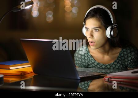 Étudiants étonnés de l'apprentissage en ligne vérifiant le contenu de leur ordinateur portable la nuit à la maison Banque D'Images