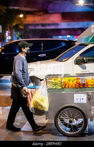 Un vendeur de fruits thaïlandais fait son chemin le long de Silom Rd. Dans le centre-ville animé de Silom, Bangkok City, Thaïlande. Banque D'Images