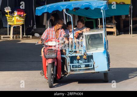 SAMUT PRAKAN, THAÏLANDE, FÉVRIER 02 2023, Un homme senior conduit un tricycle modifié pour la vente avec de petits enfants et une jeune femme Banque D'Images