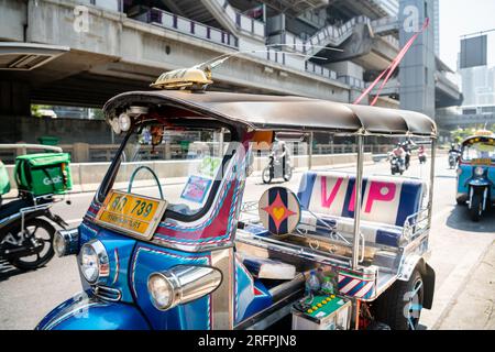 Un tuk tuk thaï classique attend devant la station aérienne de Chong Nonsi BTS dans le quartier de Chong Nonsi à Bangkok, en Thaïlande. Banque D'Images