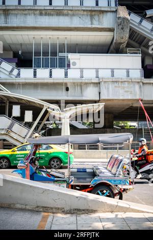 Un tuk tuk thaï classique attend devant la station aérienne de Chong Nonsi BTS dans le quartier de Chong Nonsi à Bangkok, en Thaïlande. Banque D'Images