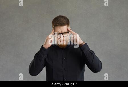 Fronçant homme souffrant de maux de tête massant les tempes studio Headshot Banque D'Images
