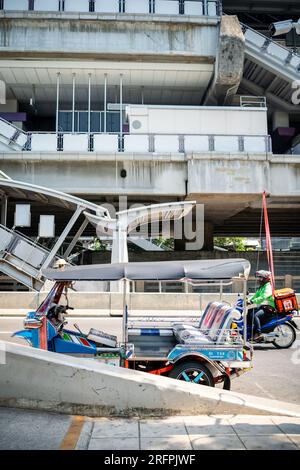 Un tuk tuk thaï classique attend devant la station aérienne de Chong Nonsi BTS dans le quartier de Chong Nonsi à Bangkok, en Thaïlande. Banque D'Images