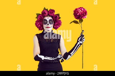 Jeune femme avec le maquillage de crâne de sucre dans la couronne de pivoines rouges Banque D'Images
