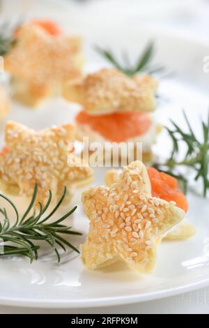 Hors-d'œuvre festif de pâte feuilletée en forme d'étoile, farcie de saumon et de fromage doux. L'apéritif parfait pour votre table de vacances. Banque D'Images