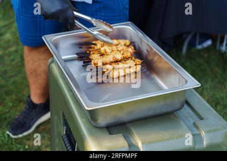 A cuire chips brochettes de poulet grillé dans un récipient en acier inoxydable lors d'une fête barbecue en été Banque D'Images