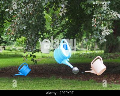 des arrosoirs pendent d'un arbre au-dessus d'une pelouse pour symboliser la rareté de l'eau Banque D'Images