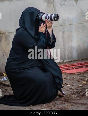 Une femme portant une abaya prend des photos à Londres. Banque D'Images