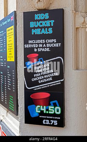 Un panneau à l’extérieur d’un plat à emporter à Weston-super-Mare, au Royaume-Uni, annonçant des repas pour enfants qui sont servis avec un seau et une pelle Banque D'Images