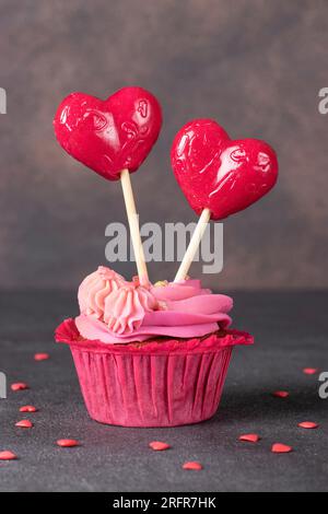 Cupcake à la crème rose décoré de sucettes en forme de cœur Banque D'Images